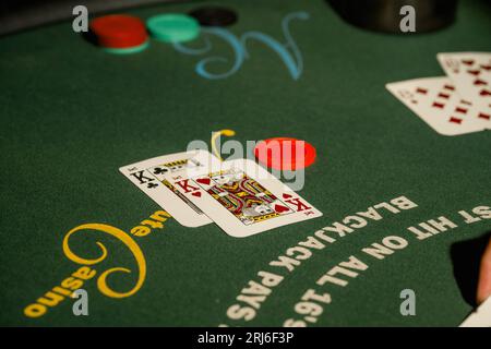 Ein grüner rechteckiger Tisch mit einer Vielzahl von Spielkarten und Poker-Chips, die in einem Casino verstreut sind Stockfoto