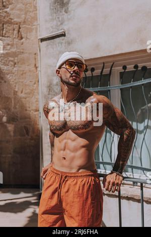 Ein junger Mann mit Tattoos posiert und genießt das sonnige Wetter an einem heißen Sommertag Stockfoto