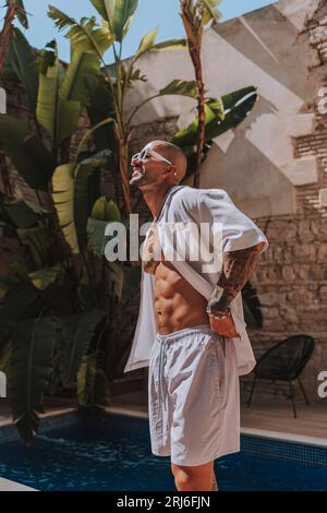 Ein junger Mann mit Tattoos posiert und genießt das sonnige Wetter an einem heißen Sommertag Stockfoto