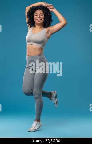 Hübsche Frau in grauer Sportswear, die energiegeladen aussieht Stockfoto