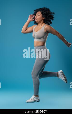 Hübsche Frau in grauer Sportswear, die energiegeladen aussieht Stockfoto