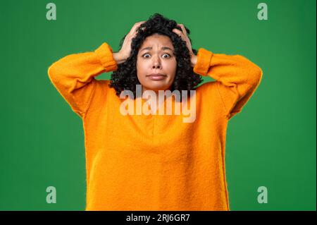 Dunkelhaarige Frau in Orange sieht gestresst und schockiert aus Stockfoto