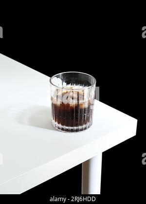 Auf einem Holztisch mit Eiskaffee befindet sich ein Glas aus glänzendem Klarglas Stockfoto