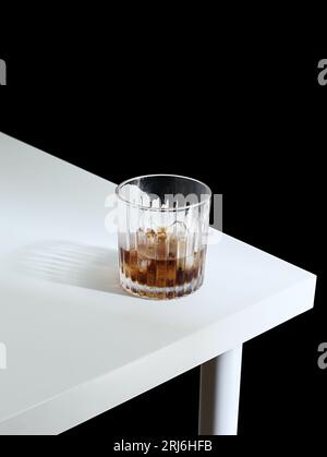 Auf einem Holztisch mit Eiskaffee befindet sich ein Glas aus glänzendem Klarglas Stockfoto