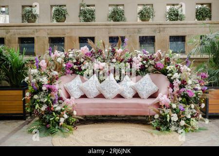 Ein rosafarbenes Sofa mit Blumendekoration und weißen Kissen Stockfoto