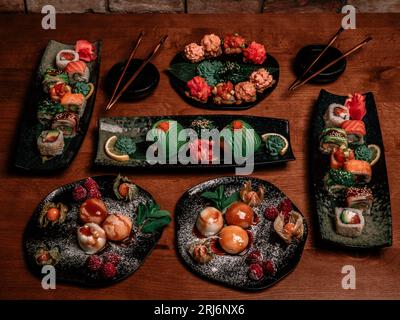 Sechs Sushi-Platten auf einem Holztisch mit dazu gehörenden Essstäbchen Stockfoto