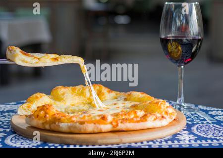 Ein köstliches georgianisches Megruli auf einem Esstisch mit einem Glas Rotwein Stockfoto