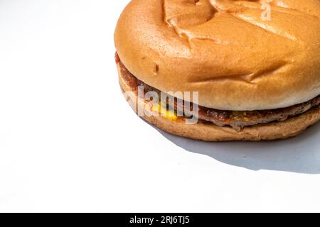 Ein köstlicher Hamburger mit einem frischen, saftigen Patty und knusprigen Toppings auf einer weißen Oberfläche mit viel Platz für Kopien Stockfoto