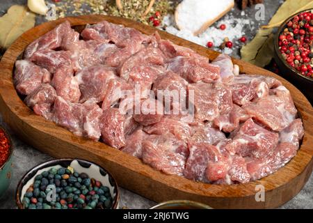 Rindfleisch gewürfelt. Frisches rohes Rindfleisch in Würfel geschnitten auf dunklem Hintergrund. Metzgerprodukte. Nahaufnahme Stockfoto