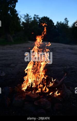 Ein orangefarbenes Leuchten strahlt von einem großen Felsblock in einer ländlichen Umgebung aus und erleuchtet die Gegend mit einem warmen, feurigen Licht Stockfoto