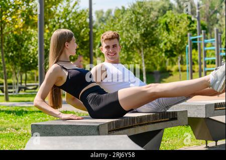 Junge Familie, die bauchmuskeltraining auf einer Parkbank macht. Mutter Vater und Tochter pumpende Presse im Park. Stockfoto