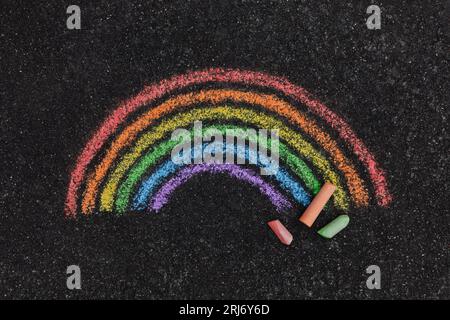 Nahaufnahme eines farbenfrohen Regenbogens, der auf einer Straße mit Kreide auf dem Bürgersteig gemalt wurde, von oben aufgenommen Stockfoto