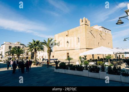 Eine Straße mit Restaurants im touristischen San Vito lo Capo vor einem blauen Himmel mit historischen Gebäuden. Stockfoto