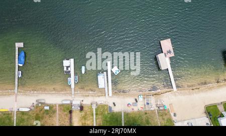 Eine Flotte von bunten Booten liegt an einer ruhigen Küste mit einem malerischen Strand im Hintergrund Stockfoto