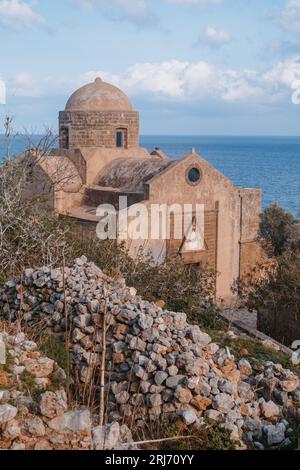 Wunderschöne religiöse Kirche mit Steinen vor dem Ozean Blick, Griechenland Stadt Monemvasia auf der Halbinsel Peloponnes, Blick mit Gebäuden und Dächern, bewölkt Stockfoto