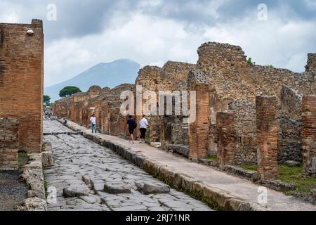 Blick nach Norden entlang der Via Stabiana, mit dem Vesuv in der Ferne, in den Ruinen der antiken Stadt Pompeji, Campania Region von Süditalien Stockfoto