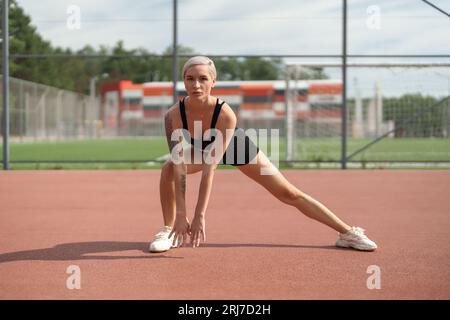 Fitness-Frau in schwarzem Outfit, das sich dehnt Stockfoto