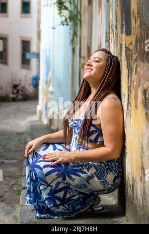 Porträt einer hübschen Frau, die sich in einem alten Haus an eine Wand beugt. Reisende Person. Pelourinho, Brasilien. Stockfoto