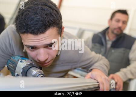Gestresste junge Arbeitskraft mit Bohrer Stockfoto