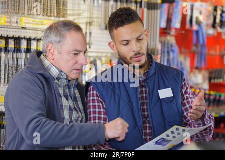 Zwei Männer, die sich den Katalog im Eisenwarenladen ansehen Stockfoto