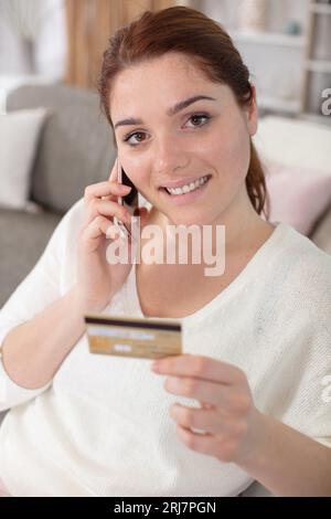 Frau mit Kreditkarte, während sie den Kauf per Telefon bestätigt Stockfoto