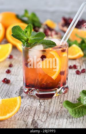 Der Cocktail wird aus Granatapfel und Orangensaft mit Tequila oder Gin mit Tonic hergestellt. Serviert in einem Glas mit Eis, orangefarbene Scheiben mit Stockfoto
