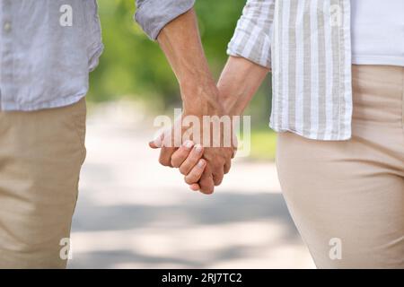 Nahaufnahme eines liebevollen, Reifen Paares, das die Hände hält, während er im Freien zusammen läuft Stockfoto