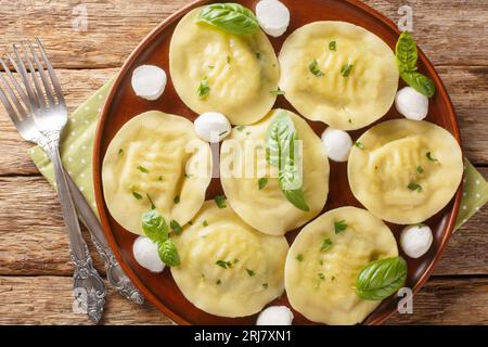 Authentische italienische Knödel Pasta Cappellacci friarielli mit Mozzarella und Kräutern aus nächster Nähe auf einem Teller auf dem Tisch. Horizontale Draufsicht von oben Stockfoto