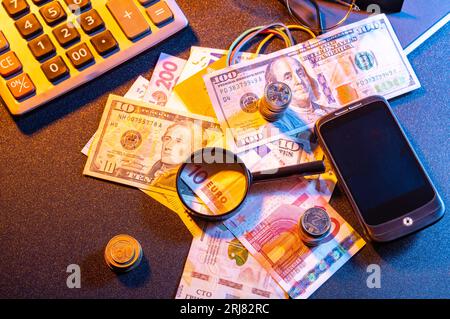 Verschiedene Währungen und Lupen. Schauen Sie sich das Geld unter einer Lupe an. Rechner und Geld. Oben. Stockfoto