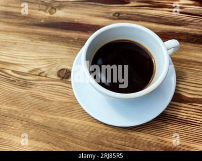 Tasse schwarzer Kaffee ohne Milch in runder weißer Tasse auf braunem Holztischhintergrund Stockfoto