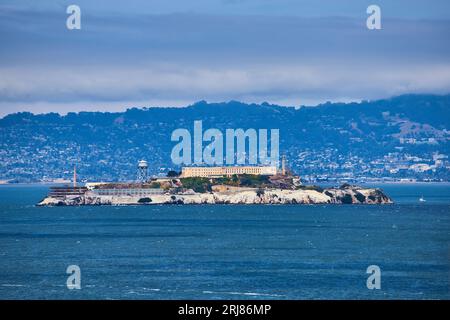 Der trübe blaue Himmel über der Insel Alcatraz mit Blick auf die Stadt auf einem Hügel im Hintergrund Stockfoto