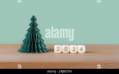 Weihnachten und Neujahr 2024 Hintergrund mit Papierbaum und Würfeln. Stockfoto
