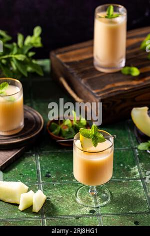Melonencocktail mit Minze im Glas auf dunkelgrünem Keramikfliesenhintergrund, Nahaufnahme. Getränke im Herbst und alkoholische Cocktails im Sommer. Alkoholischer Cocktail oder Stockfoto