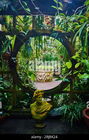 Nahansicht des Mondtores in Spalier mit Statue vor und Pflanzmaschine in der Entfernung Stockfoto