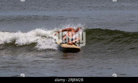 Gilgo Beach, New York, USA - 22. Juli 2023: Ein Mann, der beim Surfen am Giglo Beach vom Surfbrett ins Meer fällt. Stockfoto