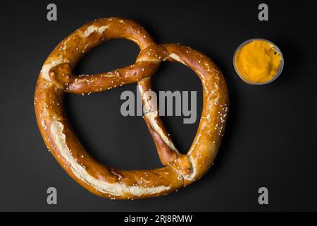 Eine Nahaufnahme einer frisch gebackenen Brezel, serviert mit einer Seite Orangensenfsauce Stockfoto