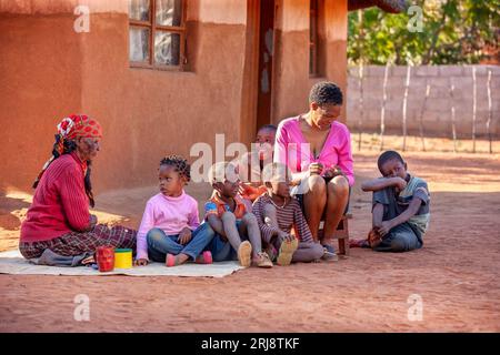 Die afrikanische Familie des Dorfes saß im Hof vor dem Haus, drei Generationen Großmutter, Mutter, Kinder. Stockfoto