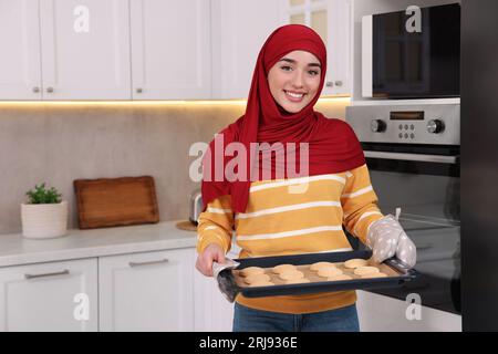 Muslimische Frau, die ein Tablett mit Keksen in der Küche hält. Leerzeichen für Text Stockfoto