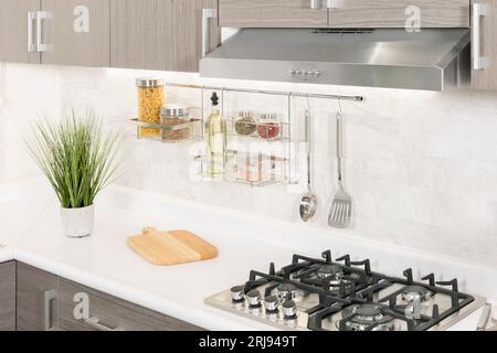 Eine moderne Küche mit weißen Arbeitsflächen und grauen Schränken mit großem Herd Stockfoto