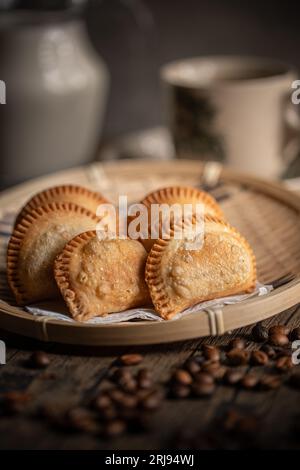 Gebratene Curry Puffs auf einem Rattan-Teller. Malaysische Snacks. Malaysisches Frühstück. Asiatische Lebensmittel. Stockfoto