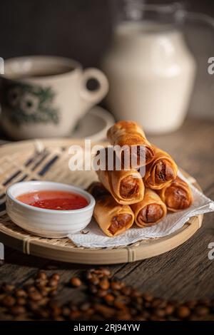 Gebratene Frühlingsrollen mit einer süßen Chilisauce auf einem Rattan-Teller. Malaysische Snacks. Malaysisches Frühstück. Asiatische Lebensmittel. Stockfoto