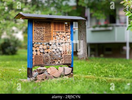 Ein Insektenhotel, das sich in einer Grasgegend neben einem Gebäude befindet, aus nächster Nähe Stockfoto