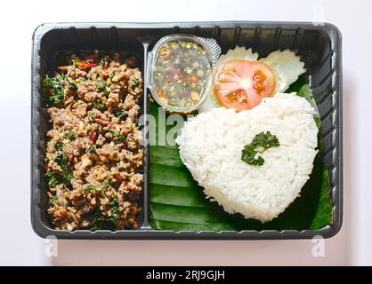 Basilikum gebratener Reis mit Schweinefleisch in Plastikbox auf dem Straßenmarkt, Fast Food in Thailand, Thailands nationale Gerichte, thailändischer Name ist Pad kra prao MoU, berühmt für seine berühmten Stockfoto