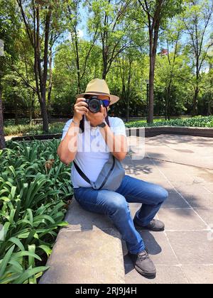 Dunkelhaariger Latino-Erwachsener ist Outdoor-Fotograf mit professioneller Kamera. Lächeln! Stockfoto