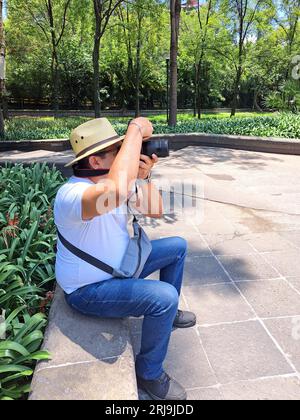 Dunkelhaariger Latino-Erwachsener ist Outdoor-Fotograf mit professioneller Kamera. Lächeln! Stockfoto