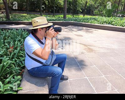 Dunkelhaariger Latino-Erwachsener ist Outdoor-Fotograf mit professioneller Kamera. Lächeln! Stockfoto