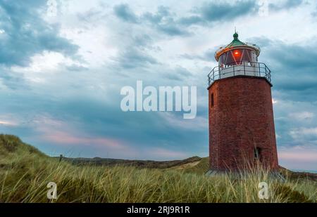 Wunderschöne Sonnenuntergangslandschaft auf der Insel Sylt, Deutschland, mit einem alten Leuchtturm unter dem bewölkten Himmel. Stockfoto
