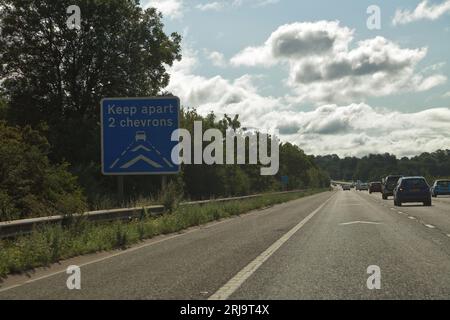 Auf einem bergab und gekrümmten Abschnitt der M4 warnt ein Warnschild davor, sich von anderen Fahrzeugen zu trennen. Stockfoto