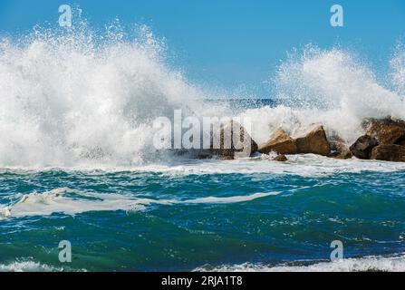 Große weiße Wellen des Meeres brechen auf den Felsen. Wellenbrecher in der Nähe des kleinen Dorfes Framura. La Spezia, Ligurien, Italien, Europa. Mittelmeer. Stockfoto