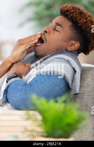 Gut aussehender junger Mann, der auf dem Sofa gähnt Stockfoto